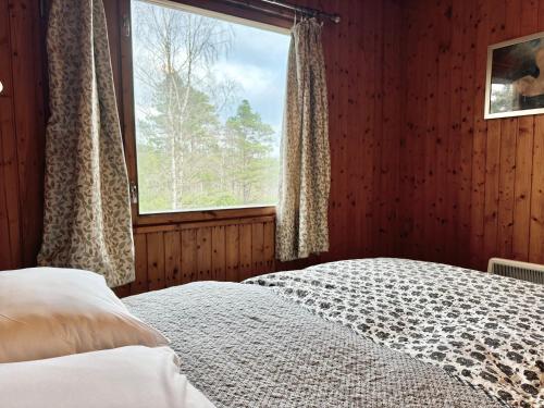 Un dormitorio con una cama y una ventana grande. en Equinox Cabin, en Torlundy
