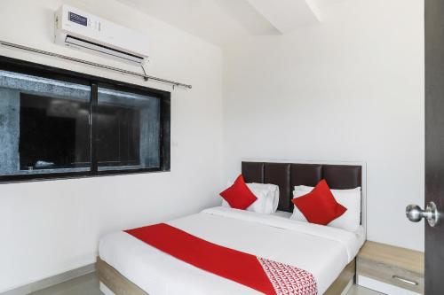 a bedroom with a bed with red pillows and a window at Hotel O Zion Inn in Vapi