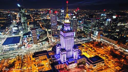 a city at night with a tall building with purple lights at Sawa 7 WiFi8Gbs 85'TV 4K Netflix in Warsaw