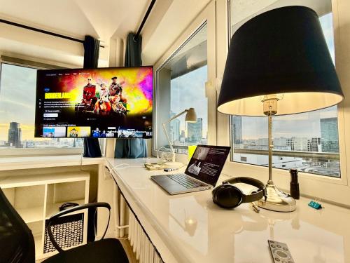 a desk with a laptop and a lamp and a television at Sawa 7 WiFi8Gbs 85'TV 4K Netflix in Warsaw