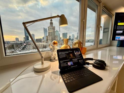 a laptop on a desk with a lamp and a window at Sawa 7 WiFi8Gbs 85'TV 4K Netflix in Warsaw