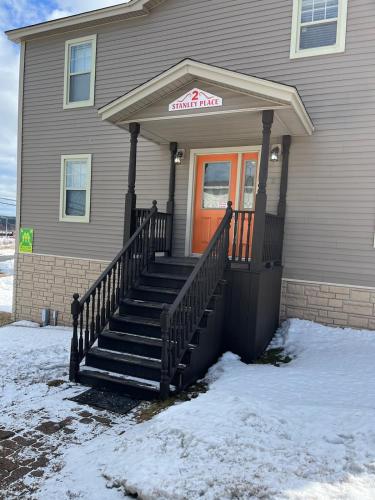 a house with a front porch with snow on the ground at Stanley House Motel in Clarenville