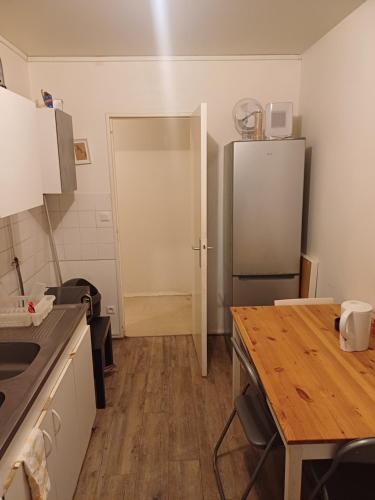 Il comprend une cuisine équipée d'un réfrigérateur et d'une table en bois. dans l'établissement Émeraude tulipe, à Nantes
