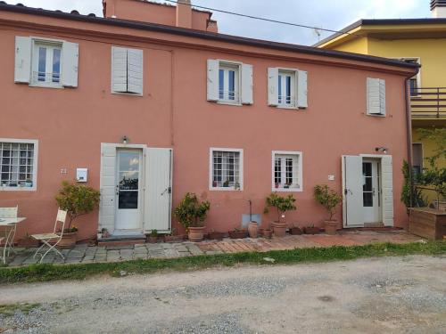 a pink house with white doors and potted plants at Casa Elicriso in Montecarlo