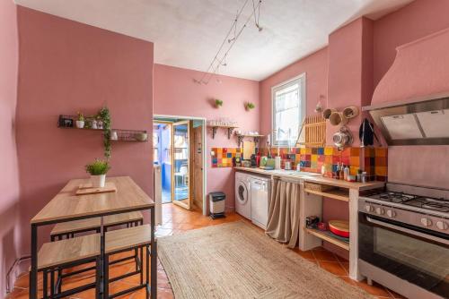 - une cuisine aux murs roses avec cuisinière et comptoir dans l'établissement Gite La Confidence, à LʼIsle-sur-la-Sorgue