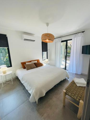 - une chambre blanche avec un grand lit et un lustre dans l'établissement Villa La Vesta Porto Vecchio, à Porto-Vecchio