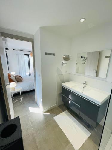 une salle de bain avec un lavabo, un miroir et un lit dans l'établissement Villa La Vesta Porto Vecchio, à Porto-Vecchio