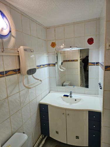 une salle de bain avec un lavabo et un miroir et des toilettes dans l'établissement Studio Au Bord de la Mer 2, au Cap d'Agde