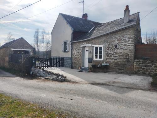 an old stone house with a white door and a fence at Chambre d'hôtes Se Sentir Libre Noisette in Crozant