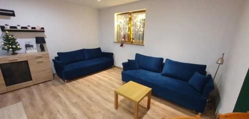 a living room with two blue couches and a table at Apartament Luna in Karpacz