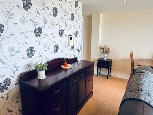 a bedroom with a dresser with a floral wallpaper at Pears Suite - 1 Bedroom - Sleeps 2 in Whitehaven