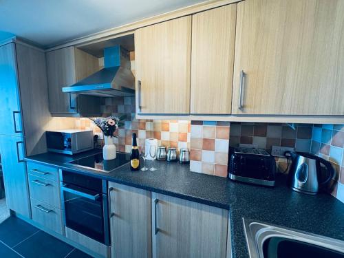 a kitchen with black counter tops and wooden cabinets at Pears Suite - 1 Bedroom - Sleeps 2 in Whitehaven