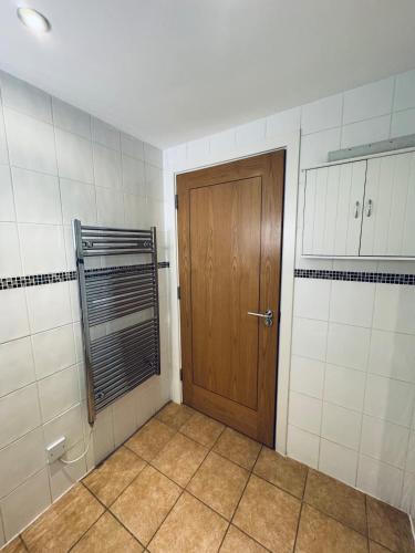 a bathroom with a wooden door and a tiled wall at Pears Suite - 1 Bedroom - Sleeps 2 in Whitehaven