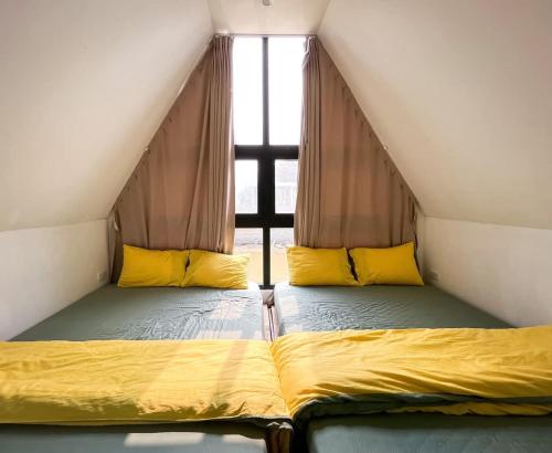 two beds in a room with a window at Kayla Homestay - Bungalow Rose Double in Ba Vì