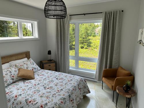 a bedroom with a bed and a chair and a window at Kabin Kamouraska 2 in Rivière-Ouelle
