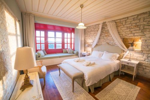 a bedroom with a bed and a couch and windows at Melikokia and Fylira two storey houses in Ano Pedina