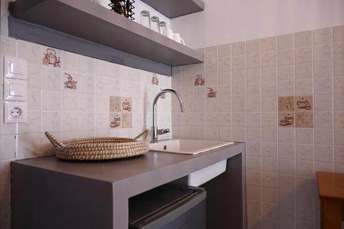 a bathroom with a sink and a basket on a counter at Oneiro Rooms Kythnos in Kanala
