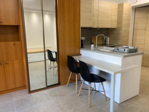 une cuisine avec un comptoir blanc et des chaises noires dans l'établissement STUDIO VIEIL ANTIBES, à Antibes