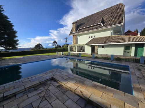 a swimming pool in front of a house at Pousada Villa Dolce Amore - Boutique Hotel in Campos do Jordão