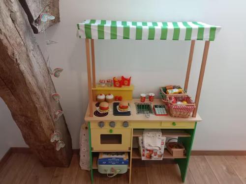 a toy desk with a play kitchen in a room at Les Blés Dorés et Les Graines de Lin, 2 gîtes à la Ferme avec moutons et piscine, à côté de Beaune in Corgengoux