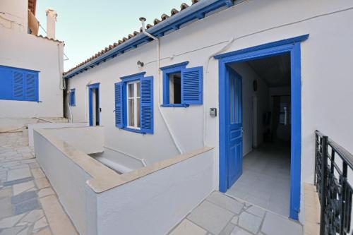 a white building with blue windows and a blue door at Aori Guest House II in Hydra