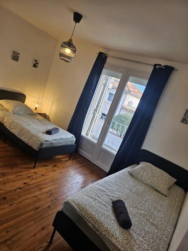 une chambre avec deux lits et une grande fenêtre dans l'établissement Le Jean Zay parking privé, à Montauban