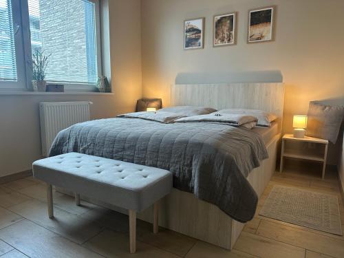 ein Schlafzimmer mit einem großen Bett mit einer Bank daneben in der Unterkunft Poznań Jeżyk-Luxury Apartment Free Parking in Posen