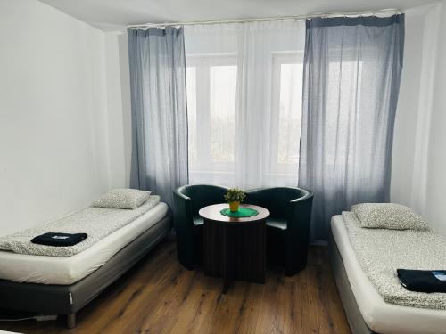 a room with two beds and a table and a window at Pokoje Gościnne Strumykowa in Lublin