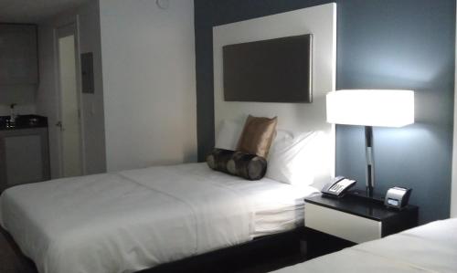 a hotel room with a bed with a lamp and a phone at Lotus Boutique Inn and Suites in Ormond Beach