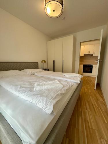 a large white bed in a room with a kitchen at COHO City Apartments mit hauseigener Tiefgarage in Vienna