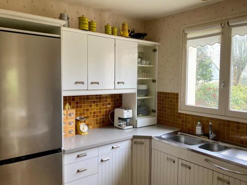 a kitchen with white cabinets and a stainless steel refrigerator at Maison aux camélias in Locquénolé