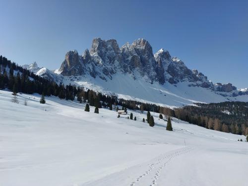 a snow covered mountain with a bench in the foreground at Dolomiten Home in Villnoss