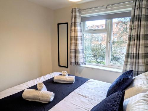 a bedroom with a bed with two pairs of slippers on it at Theatre Severn Town House, Parking & Quarry Views in Shrewsbury