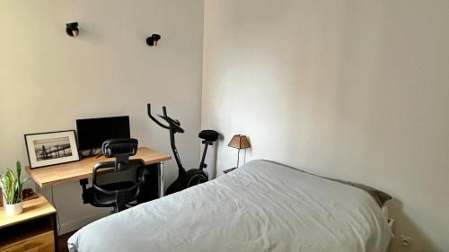 une chambre avec un lit et un bureau avec un ordinateur dans l'établissement Charmant 2 pièces calme proche Paris, à Cachan