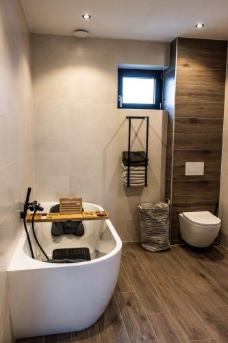 a bathroom with a bath tub and a toilet at The White House Apartment in Tholen