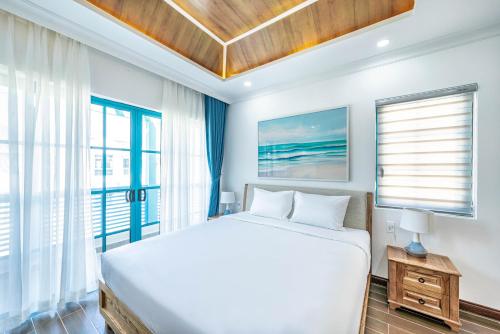 a white bedroom with a bed and a window at DT Retreat - Biệt thự nguyên căn - 3 Phòng ngủ - Novaworld Phan Thiết in Phan Thiet