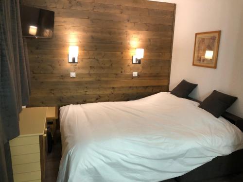 a bedroom with a white bed and a wooden wall at Studio 28m2 vue pistes plein sud du dimanche au dimanche in La Plagne