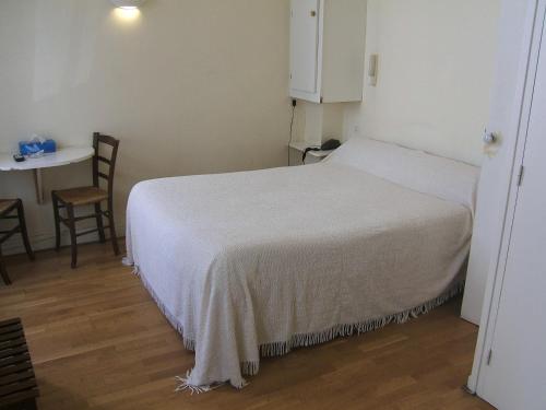 a bedroom with a white bed with a table and a chair at Hotel Saint Jean in Chalon-sur-Saône