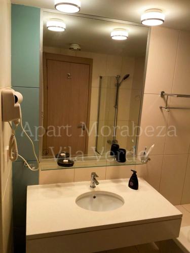 un bagno con un lavandino e un grande specchio di Morabeza Vila Verde a Santa Maria
