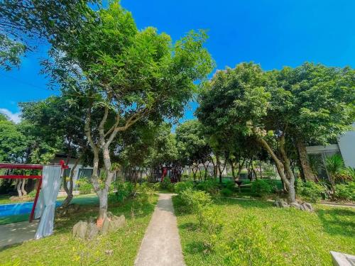 a path in a park with trees and a building at Kayla Homestay - Bungalow Rose Double in Ba Vì