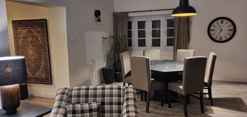 a dining room with a table and chairs and a clock at Vendia Cottage in Nathia Gali