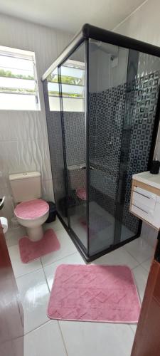 y baño con ducha y aseo con esterillas rosadas. en Casa marcius, en Monte Verde