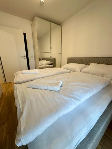 a large white bed with a towel laying on it at COHO City Apartments mit hauseigener Tiefgarage in Vienna