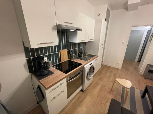 a kitchen with white cabinets and a washer and dryer at Marine 1 in Cherbourg en Cotentin