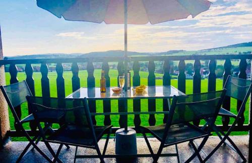 une table et des chaises sur un balcon avec un parasol dans l'établissement Superbe F3 au pied des pistes avec Piscine chauffée, à Métabief