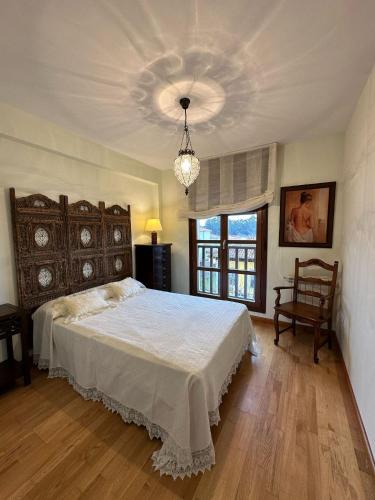 a bedroom with a large bed and a chandelier at Cuevas del Mar in Nueva de Llanes