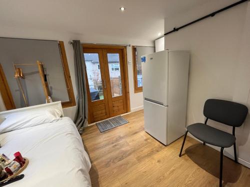 a bedroom with a bed and a refrigerator and a chair at The Grove self-contained Garden Suite in Bexleyheath