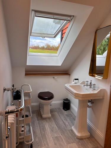 a bathroom with a sink and a toilet with a window at Gorgeous modern countryside loft in Bath