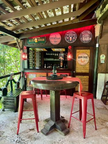 a table and two red stools in front of a bar at Platon Ecolodge in Santa Cruz de Barahona