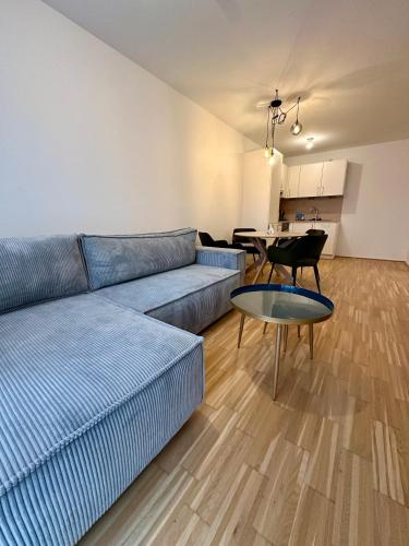 a living room with a blue couch and a table at COHO City Apartments mit hauseigener Tiefgarage in Vienna
